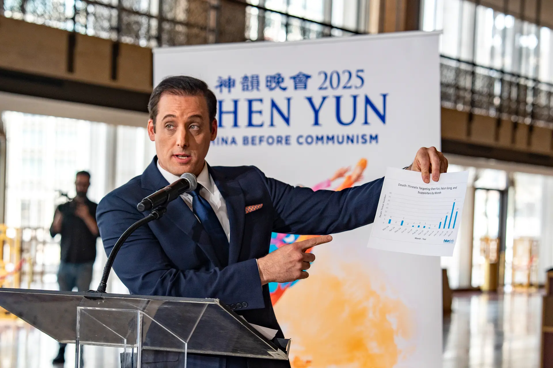 El presentador de Shen Yun, Leeshai Lemish, sostiene un gráfico que muestra el número de amenazas de muerte dirigidas contra Shen Yun, Falun Gong y sus seguidores, en una conferencia de prensa que destaca la represión transnacional del Partido Comunista Chino, en el Lincoln Center de la ciudad de Nueva York, el 26 de marzo de 2025. (Samira Bouaou/The Epoch Times).